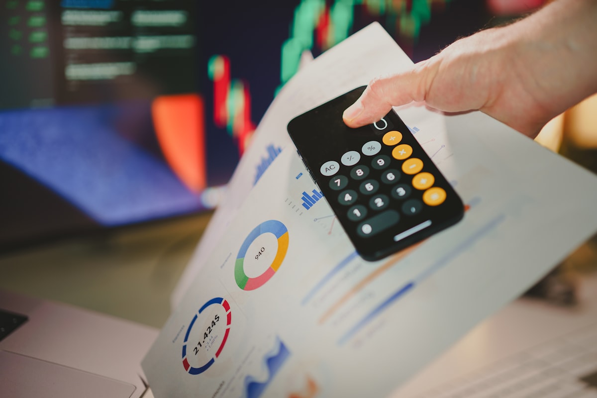 Close detail of a calculator held over financial documents on a desk