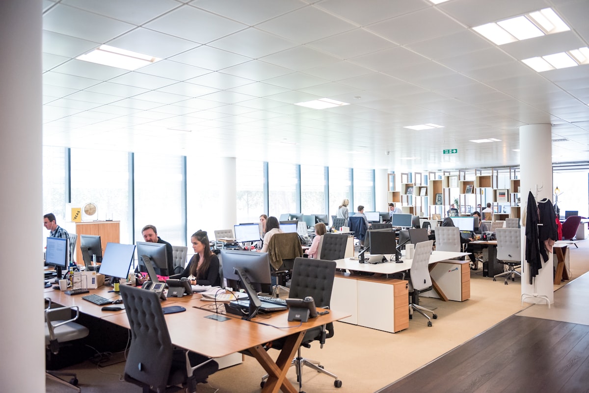 A busy open-plan office with people working at rows of desks
